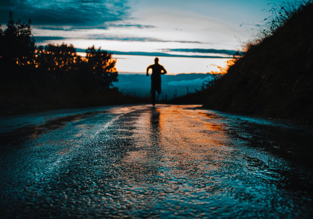 silhouette photo of a person running on road