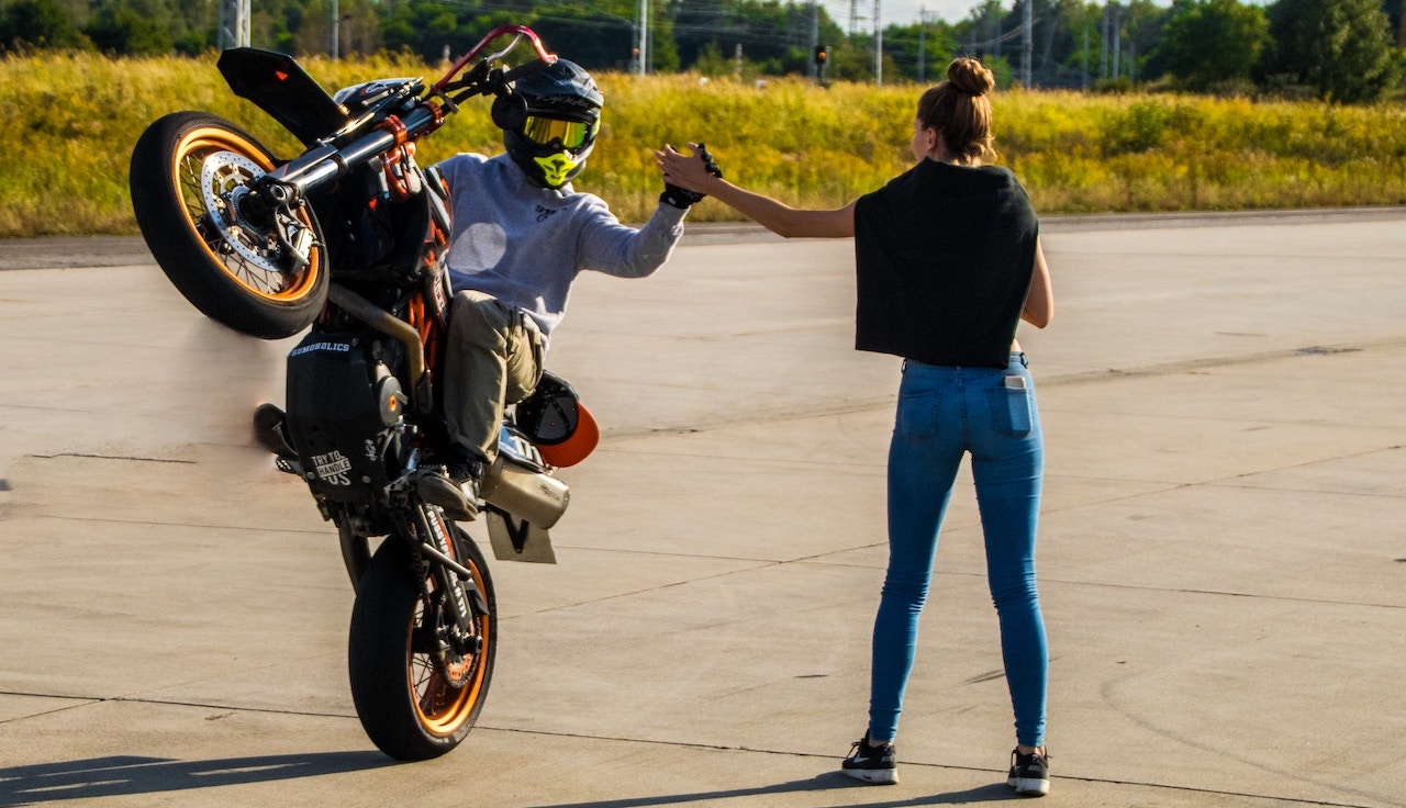 man in black t-shirt and blue denim jeans riding motorcycle on road during daytime